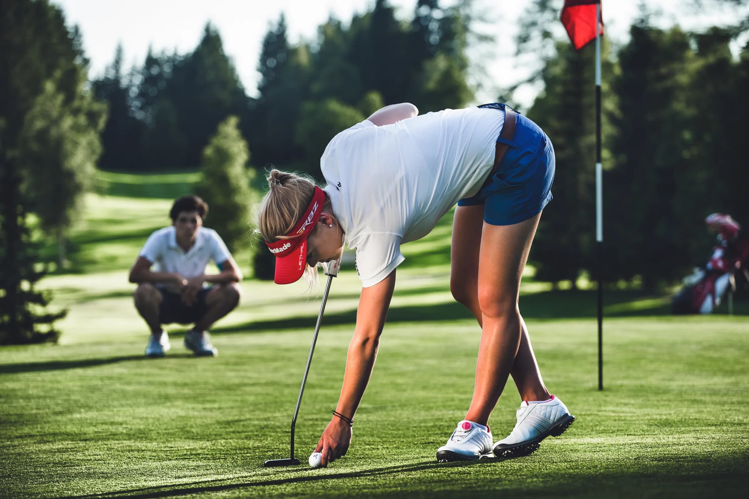 Eine Golferin hebt einen Ball aus dem Loch im Golfclub Seefeld-Wildmoos